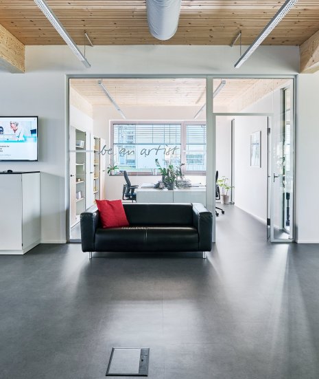 wineo PURLINE Bioboden im Büro Loft Style moderne Einrichtung Sofa dunkle Fliesen Fußboden
